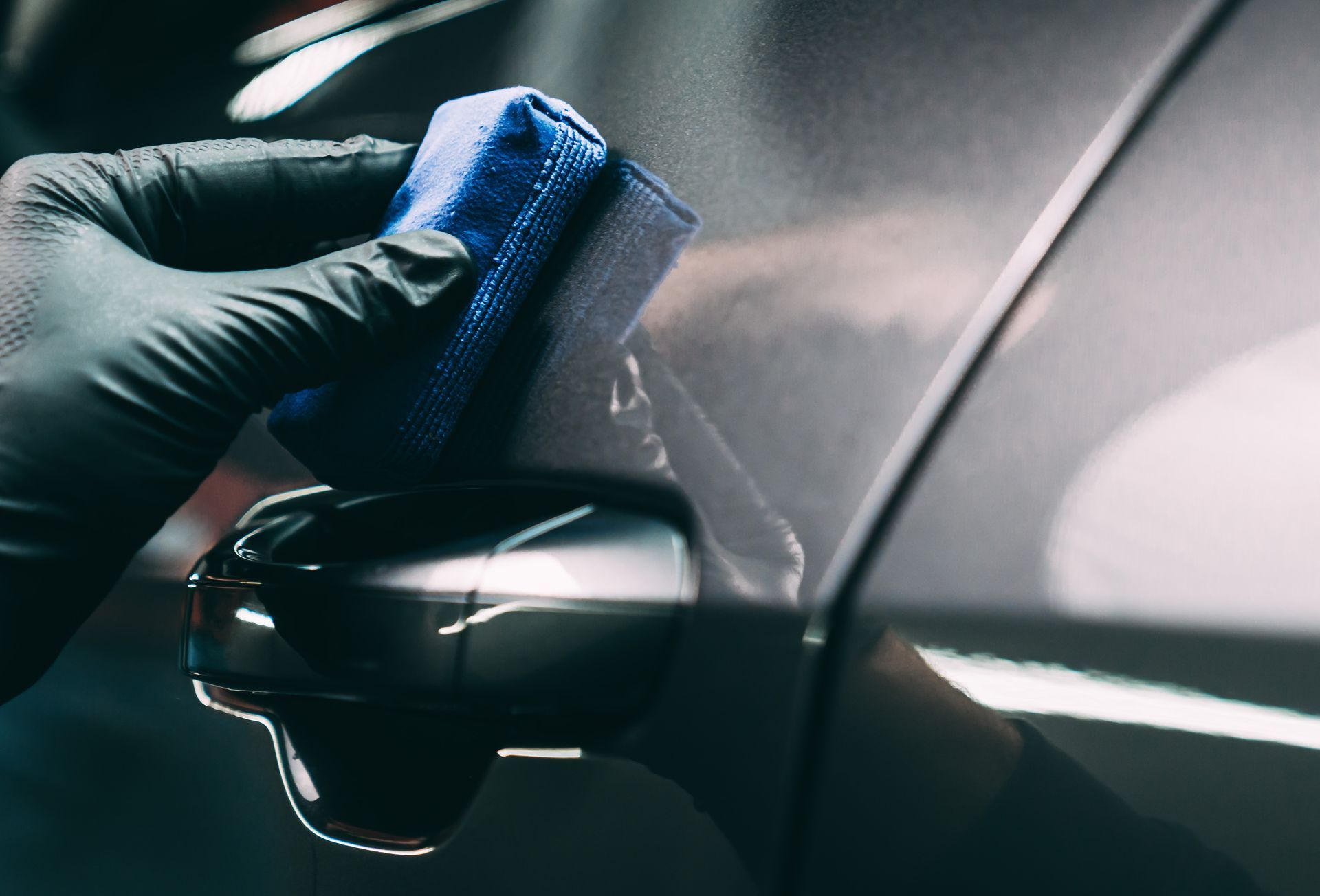 A person is polishing a car with a blue sponge.