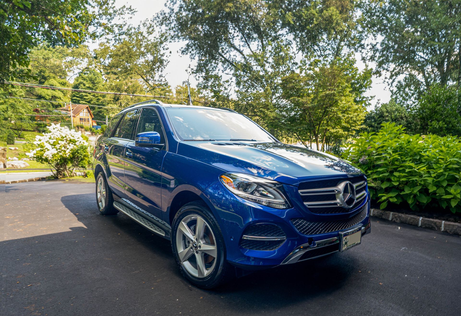 a blue mercedes benz gle suv is parked in a driveway .