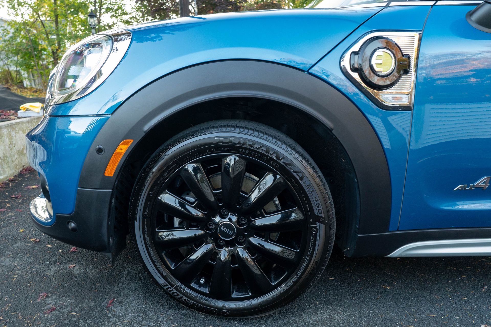 A blue mini cooper with black wheels is parked in a driveway.