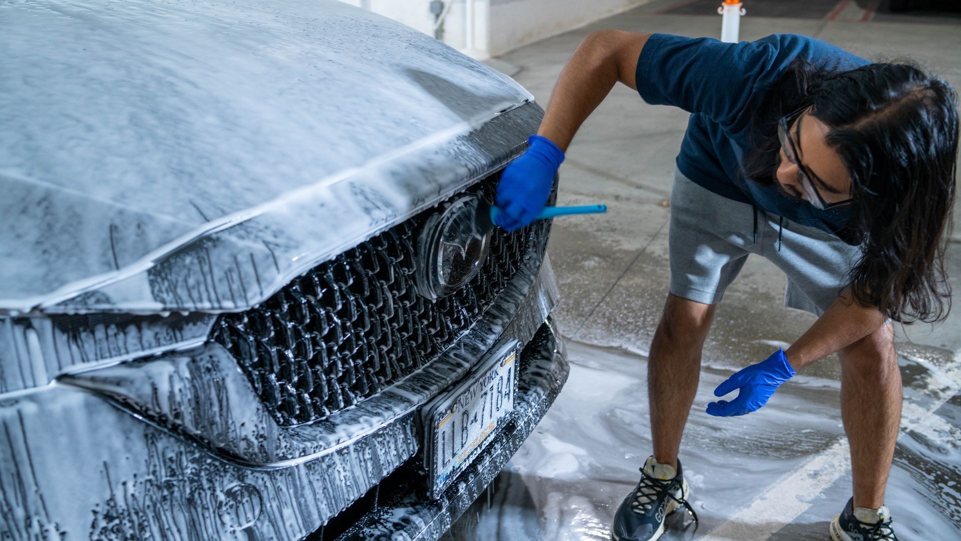 Man detailing and washing grey Toyota car by hand