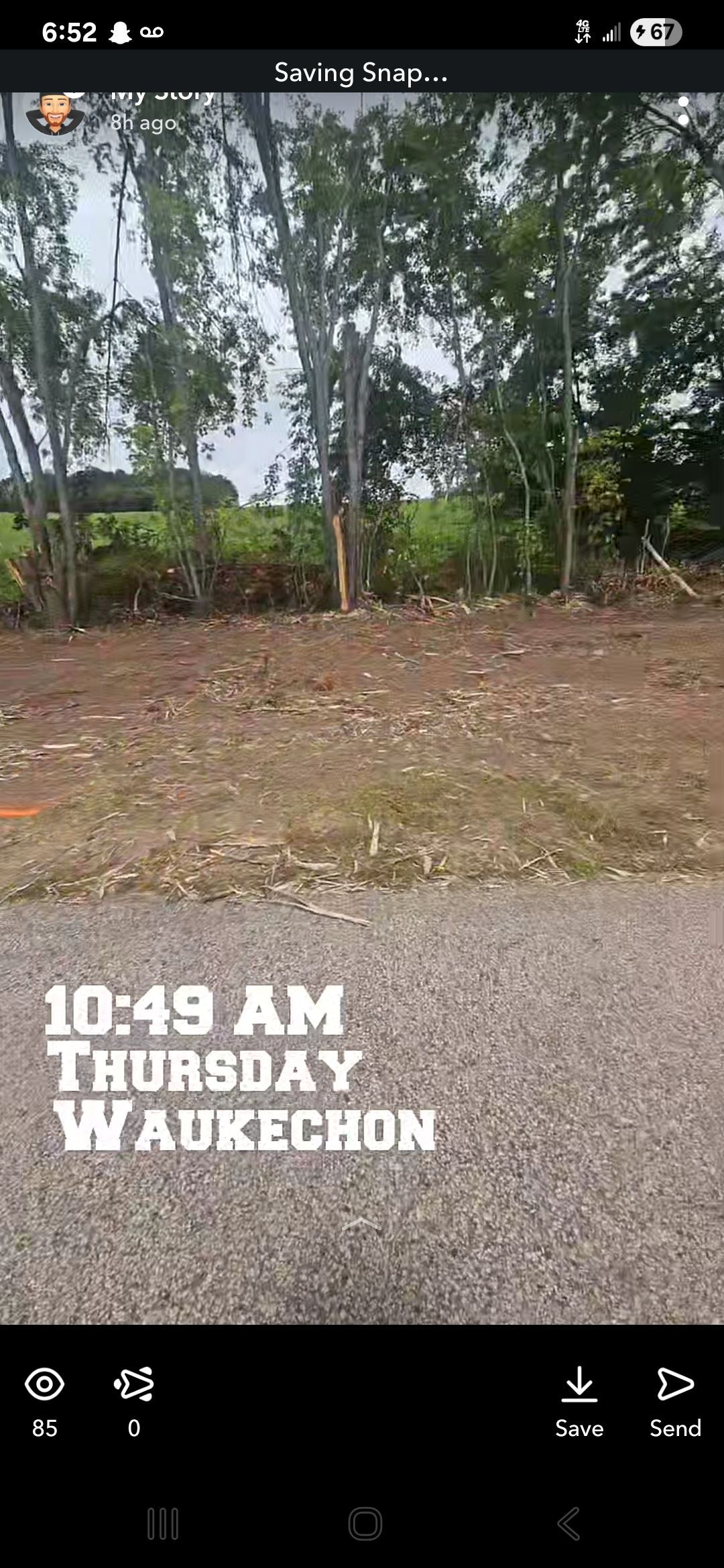A gravel road and dirt area in front of trees. Time stamp: 10:49 AM Thursday Waukecbon.