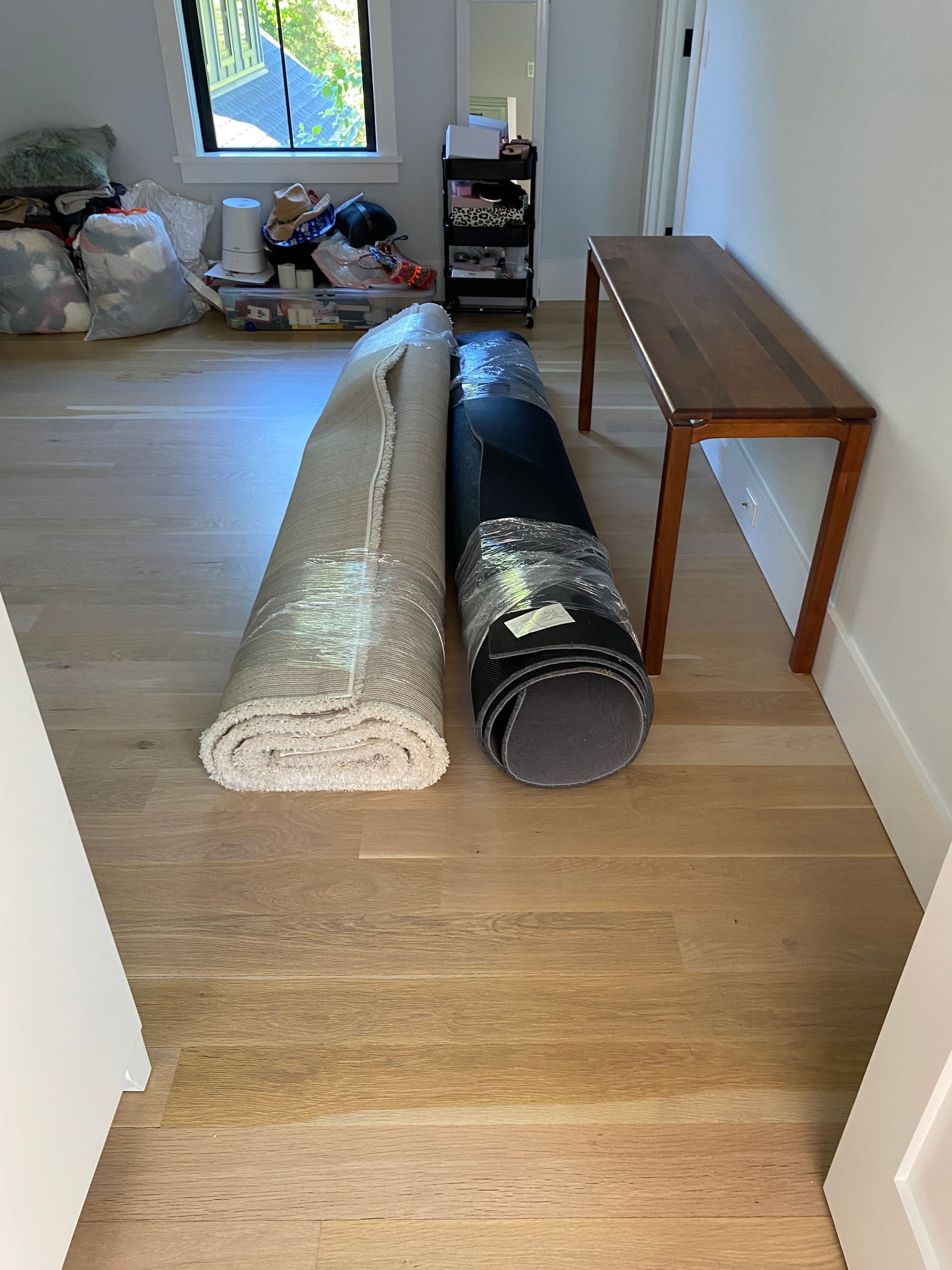 A rolled up rug is sitting on a wooden floor next to a wooden table.