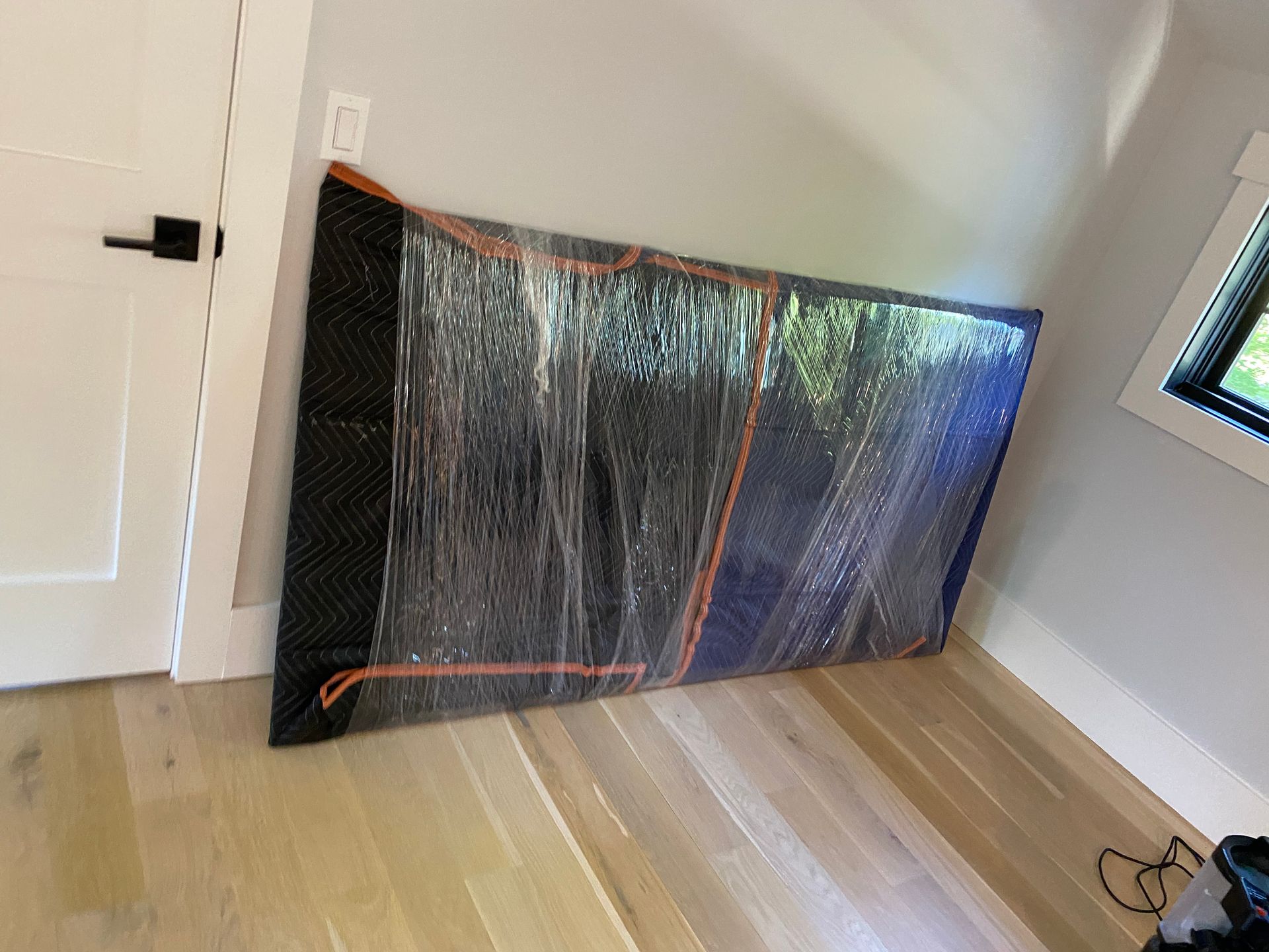 A large piece of furniture is wrapped in plastic in a room.