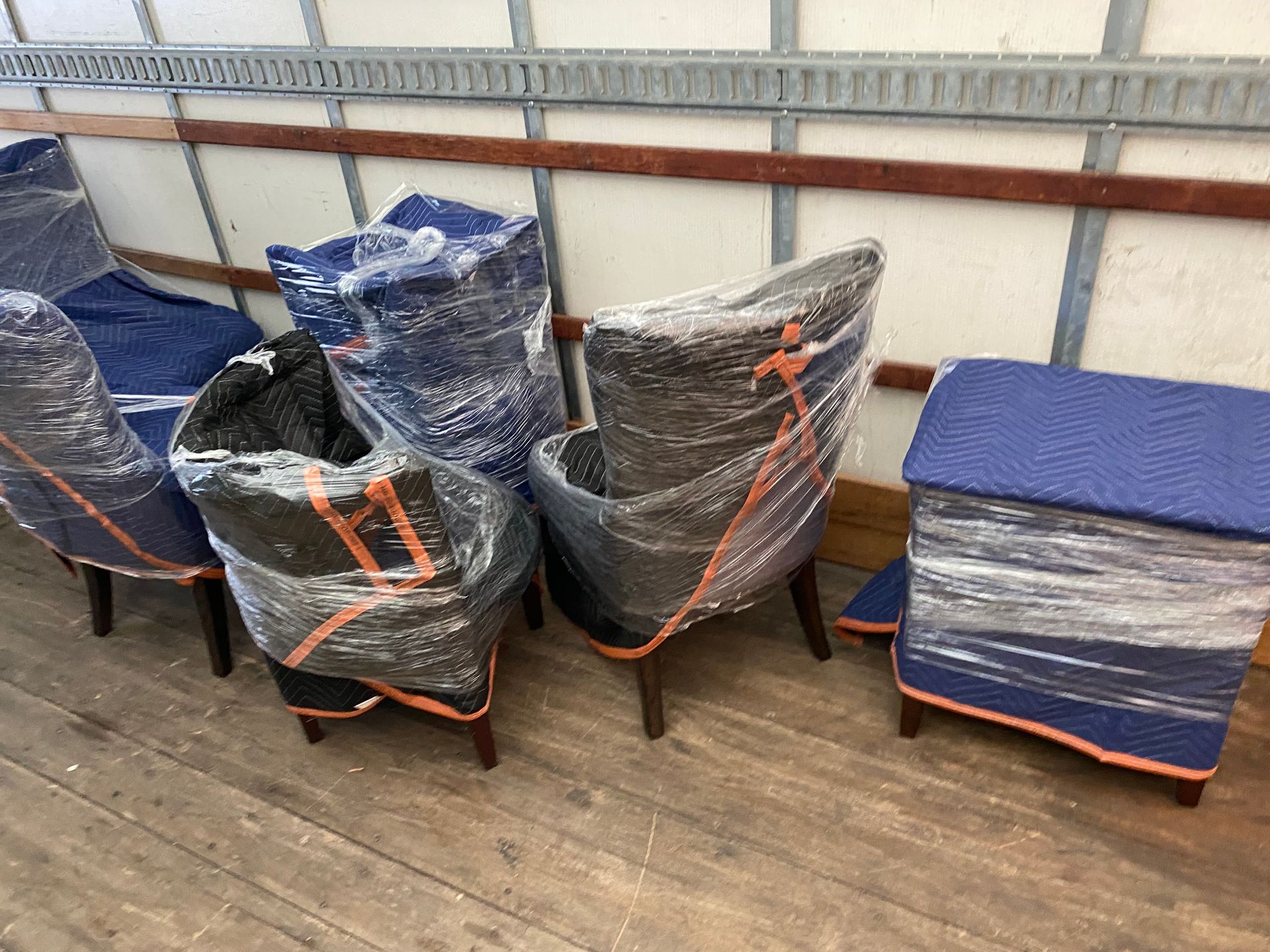 A group of chairs wrapped in plastic are sitting on a wooden floor.