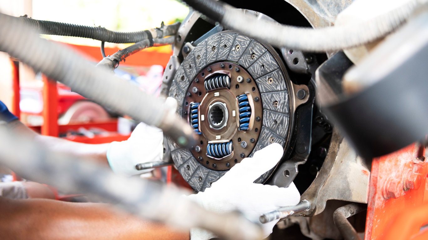 A close up of a person working on a clutch on a car.