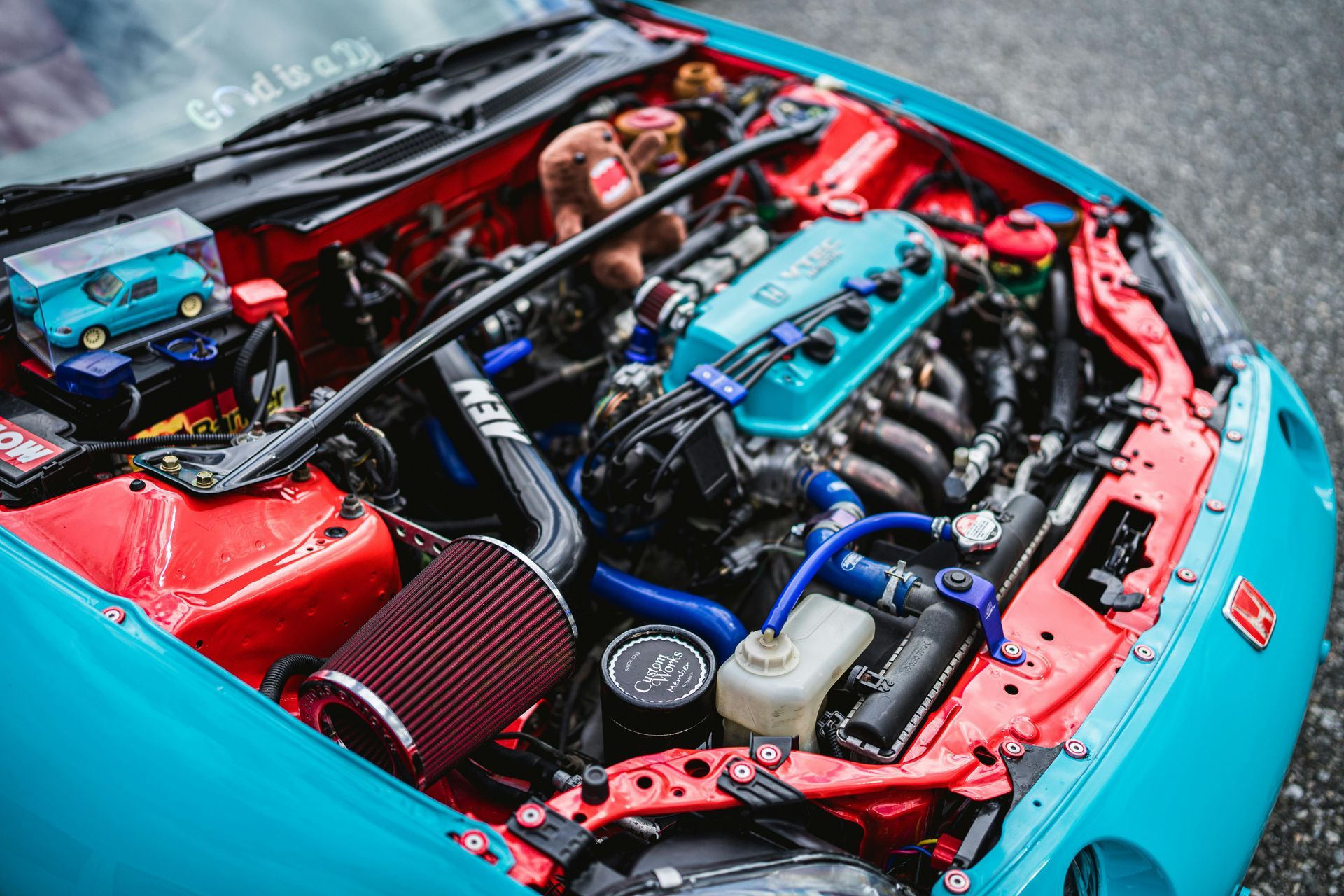 The engine of a red and blue car is visible under the hood.
