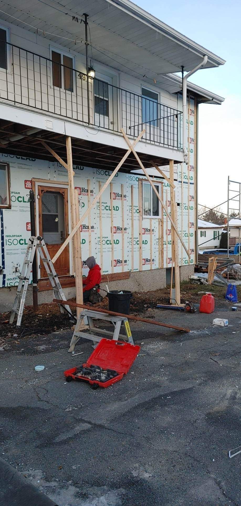 Un bâtiment est en cours de rénovation avec une boîte à outils rouge devant lui.