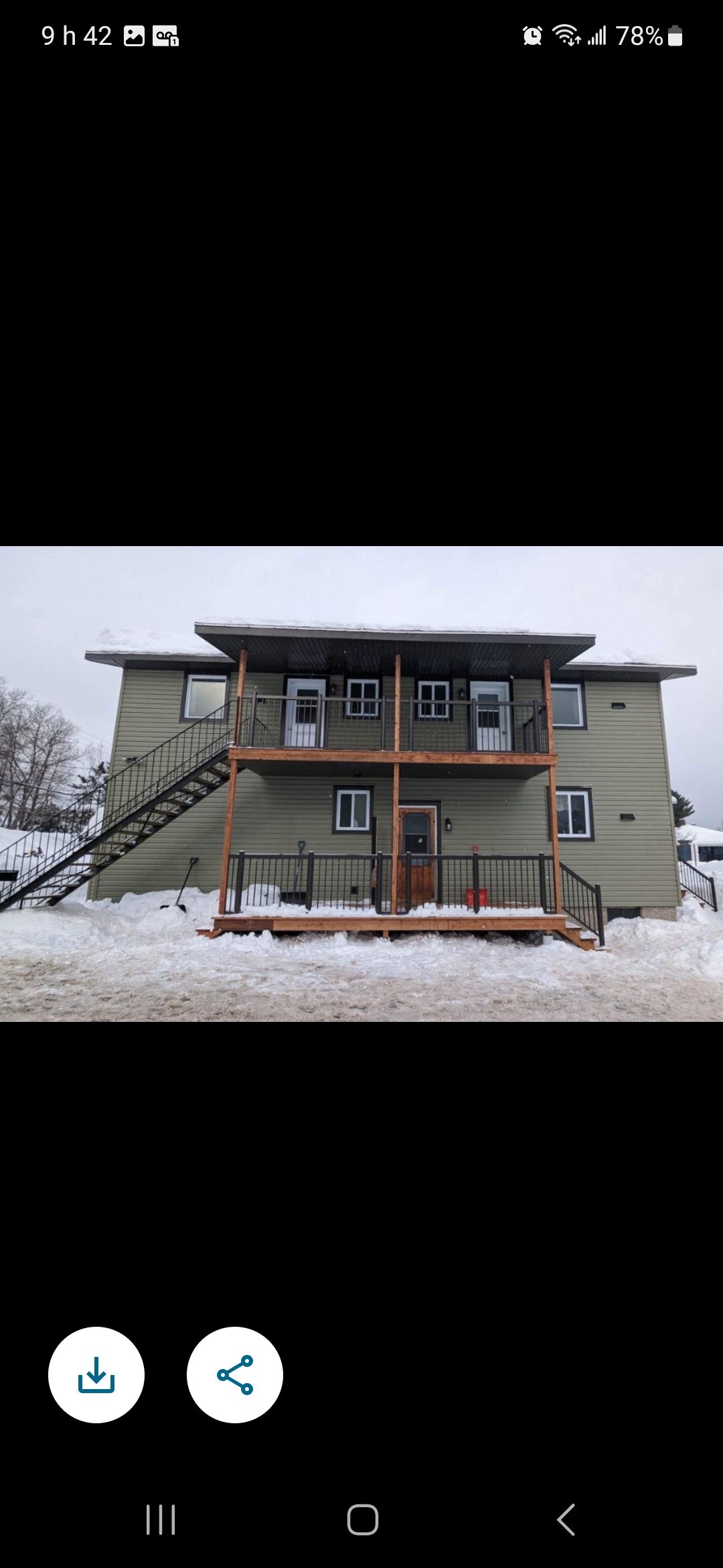 Une grande maison avec une terrasse et des escaliers dans la neige.