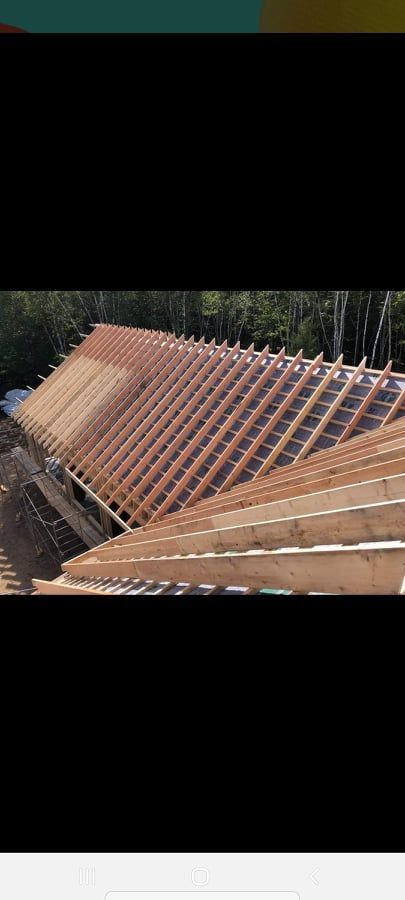 Un grand toit en bois est en construction dans les bois.