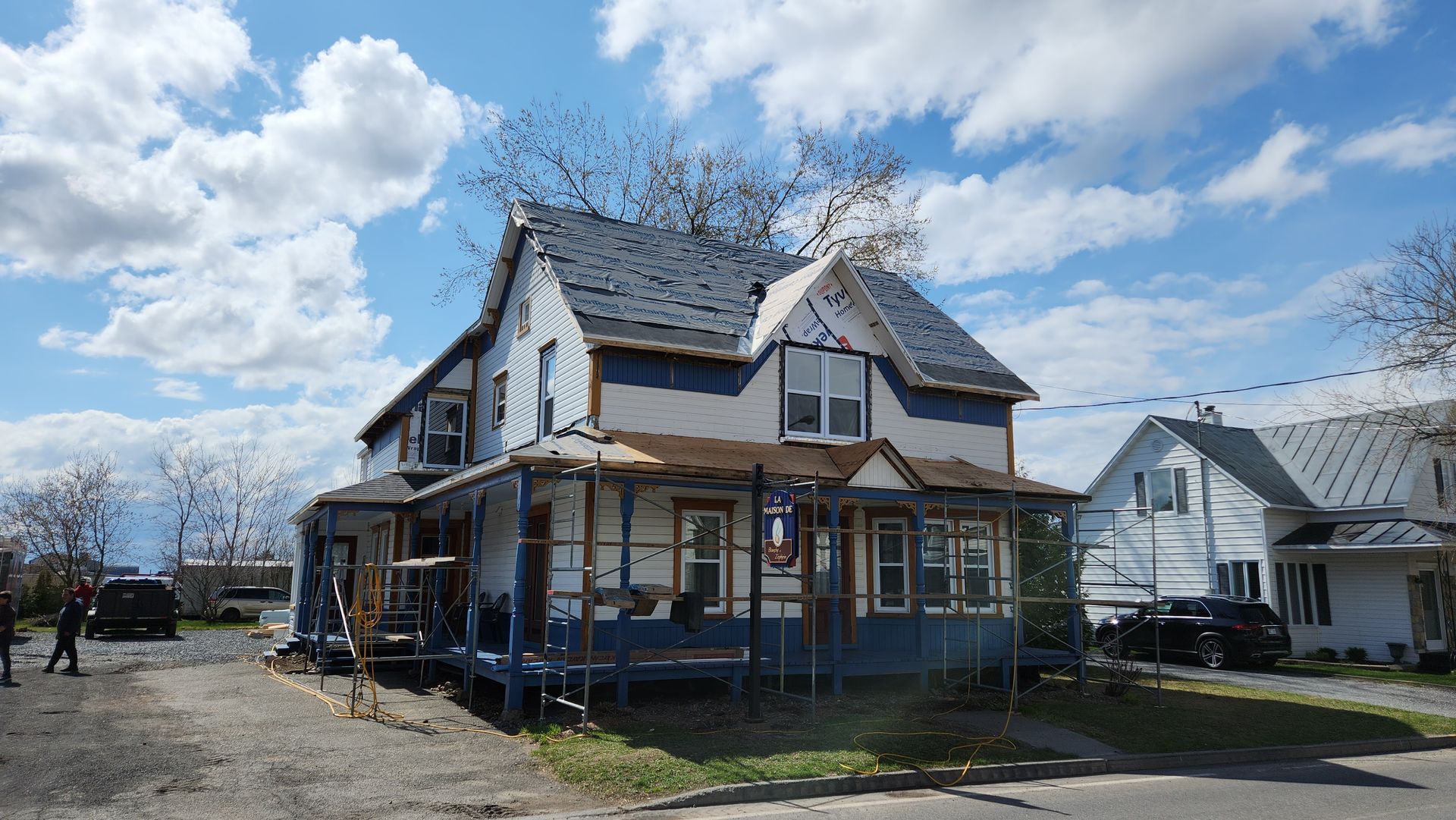 Une maison bleue au toit blanc se trouve sur un chemin de terre.