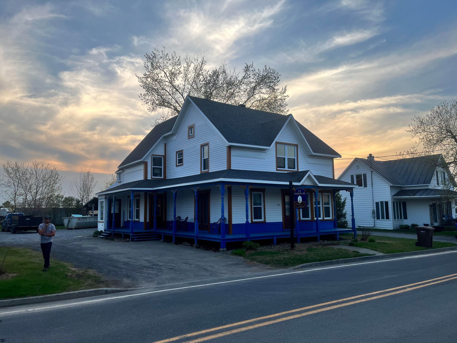 Une maison blanche avec un porche bleu se trouve au bord de la route.