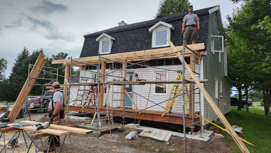 Un homme se tient sur le toit d’une maison en construction.