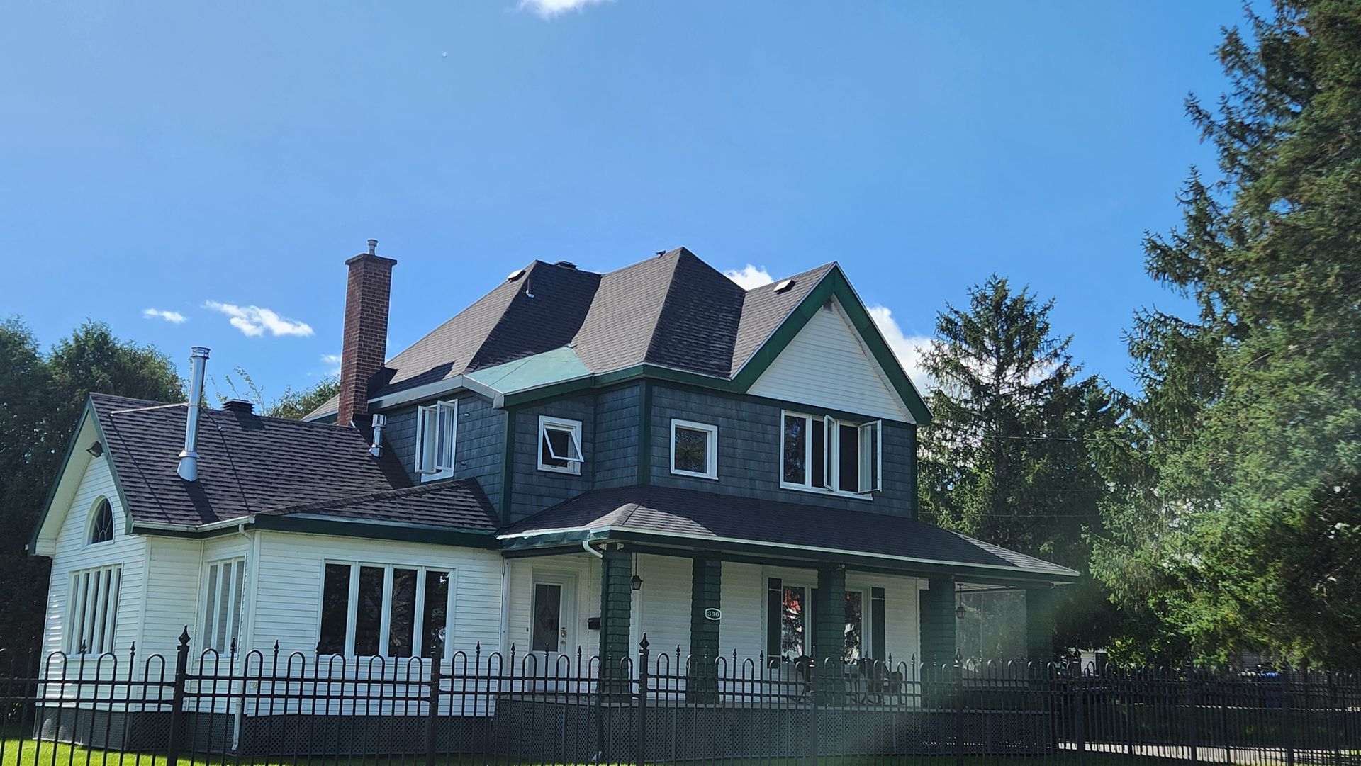 Une grande maison blanche entourée d’une clôture noire