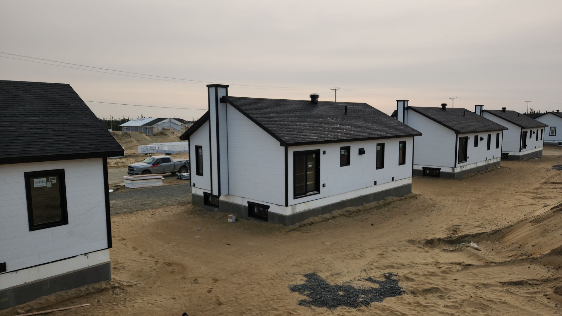 Une rangée de petites maisons blanches se dresse au sommet d’un champ de terre.