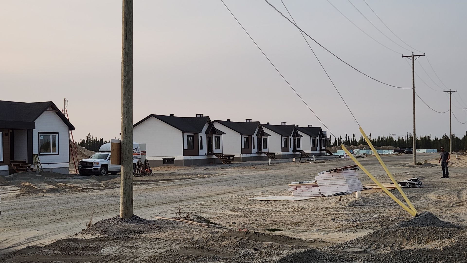 Une rangée de maisons est en construction sur un chemin de terre