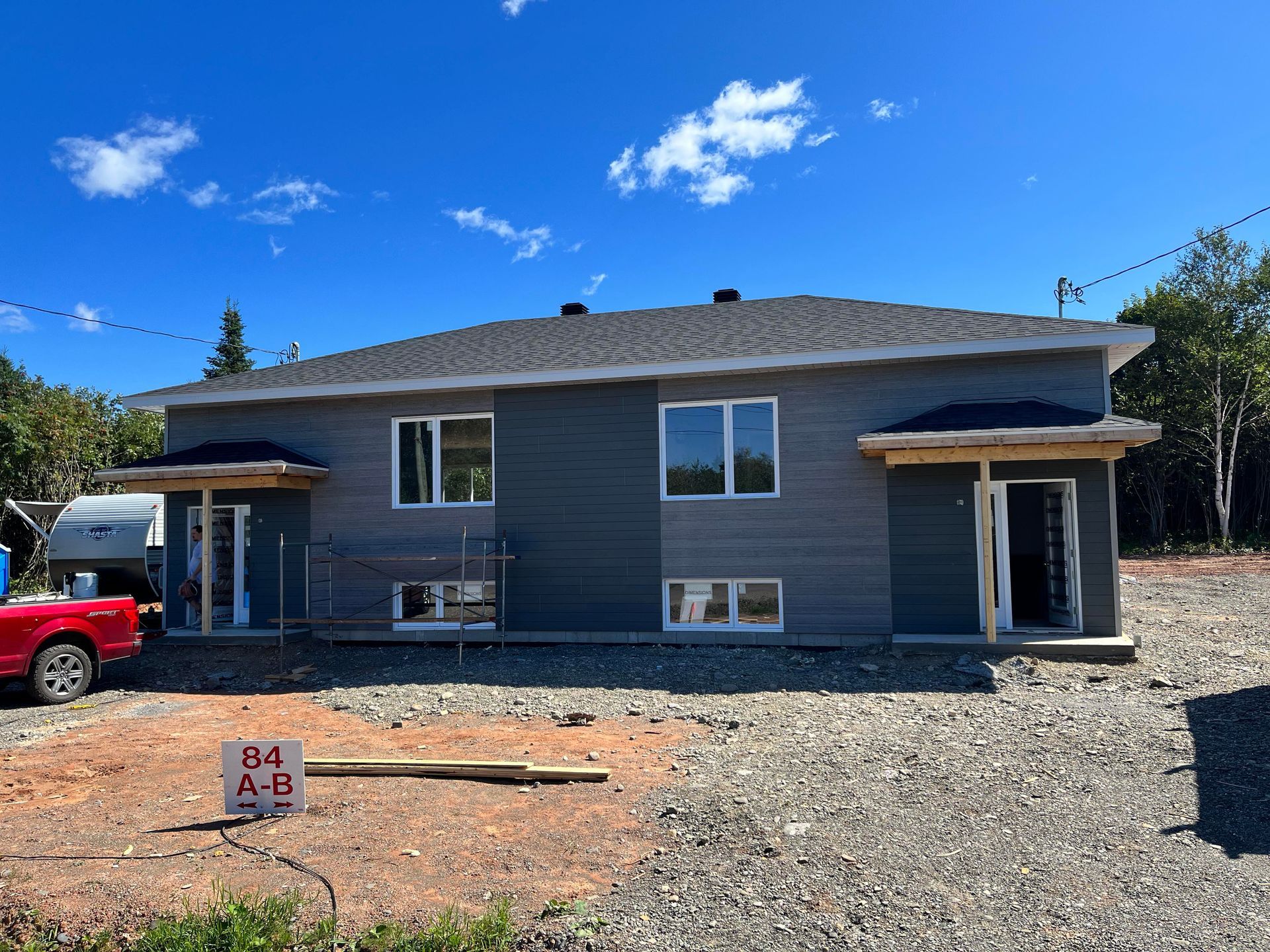 Un camion rouge est garé devant une maison en construction.