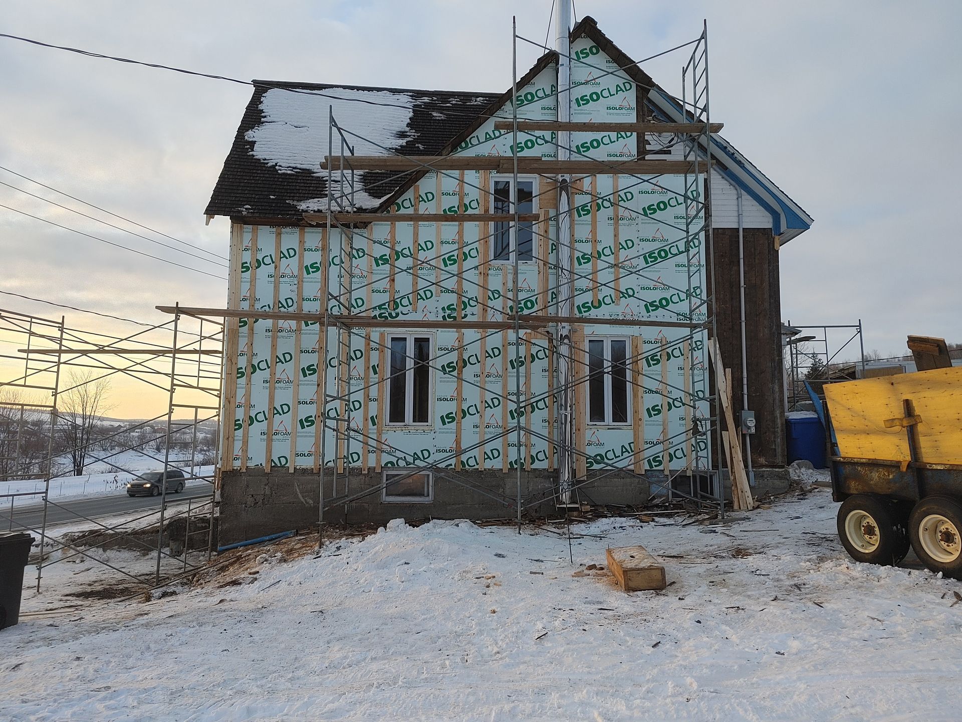 Une benne jaune est garée devant une maison en construction