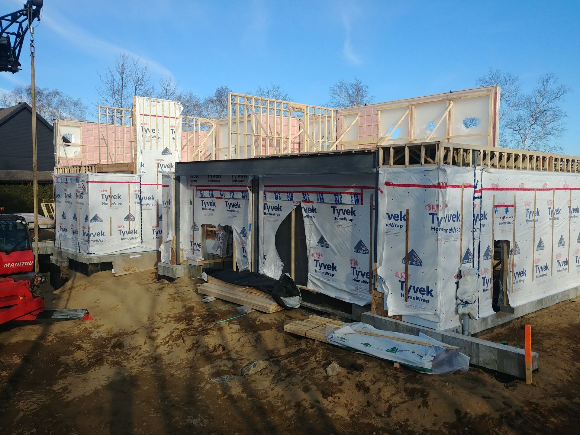 Une maison est en construction dans la terre avec une grue en arrière-plan.