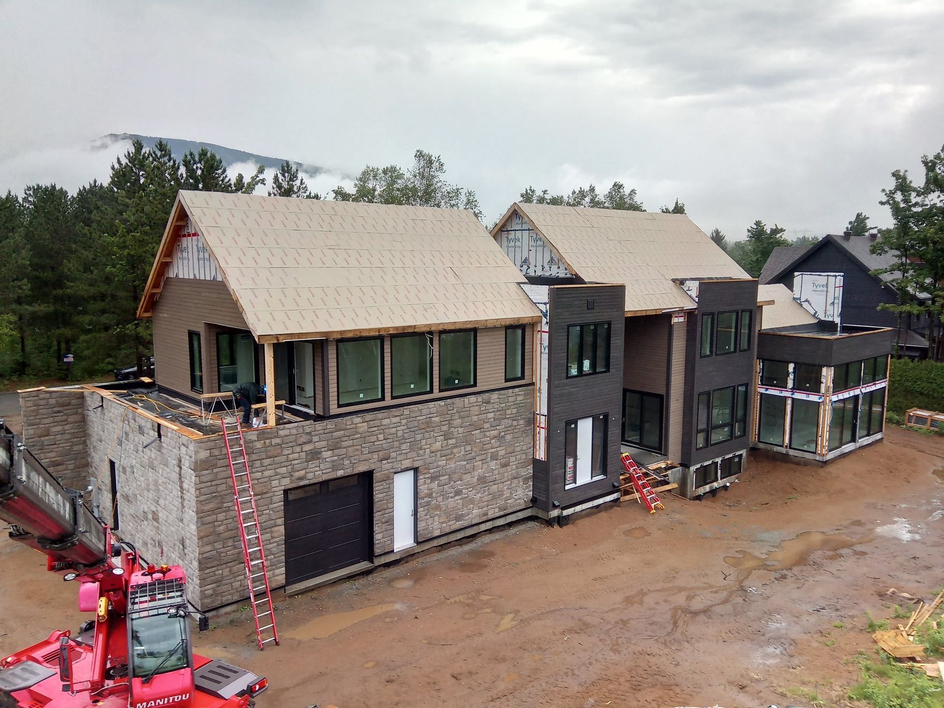Une grande maison est en construction au milieu d’un champ de terre.