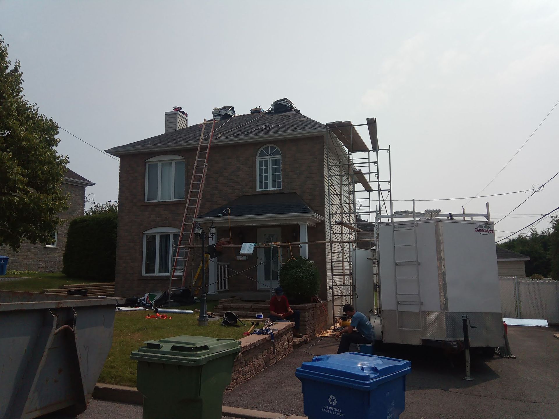 Une maison en brique avec une caravane blanche garée devant elle