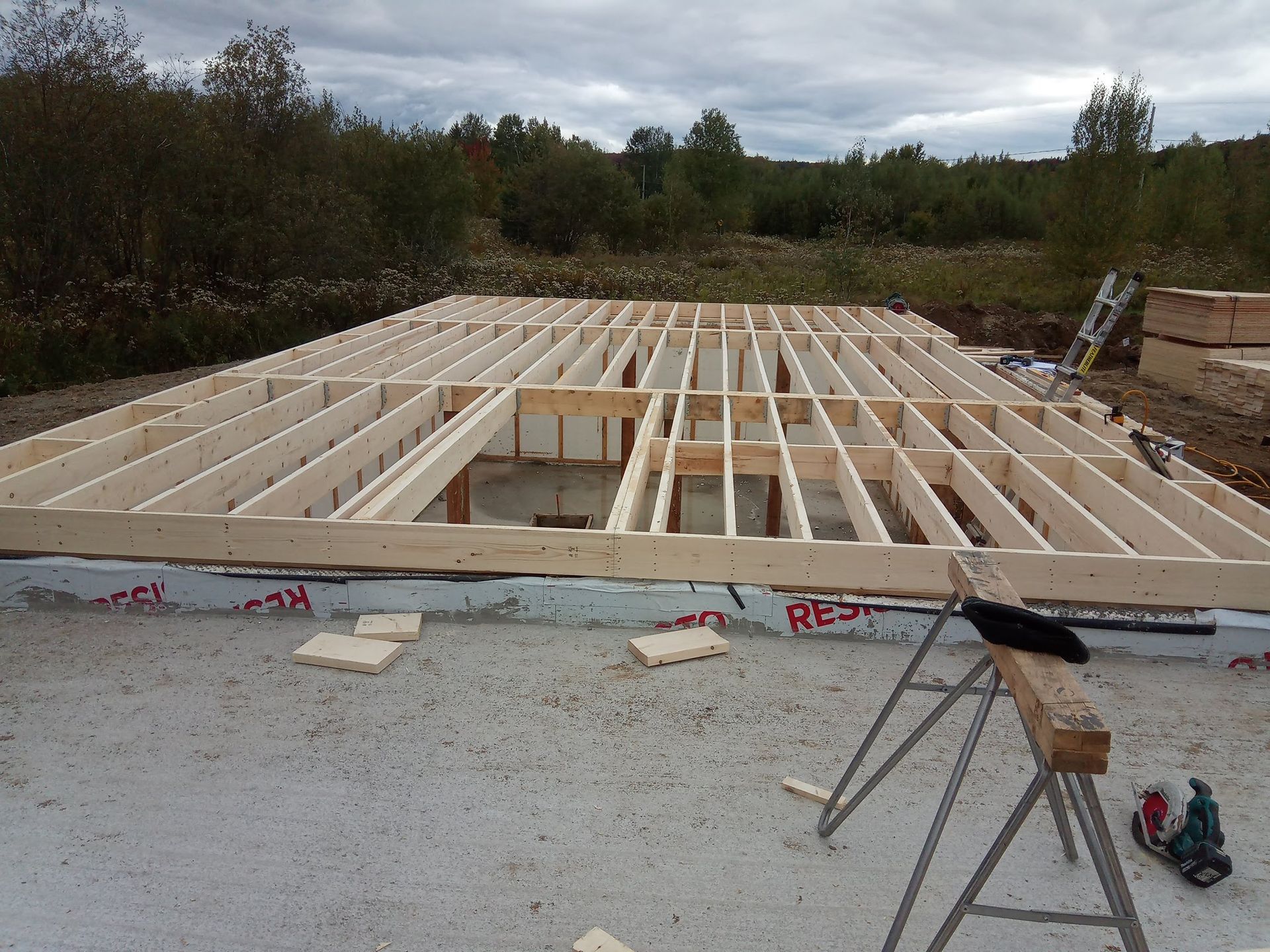 Une charpente en bois repose sur un sol en béton.