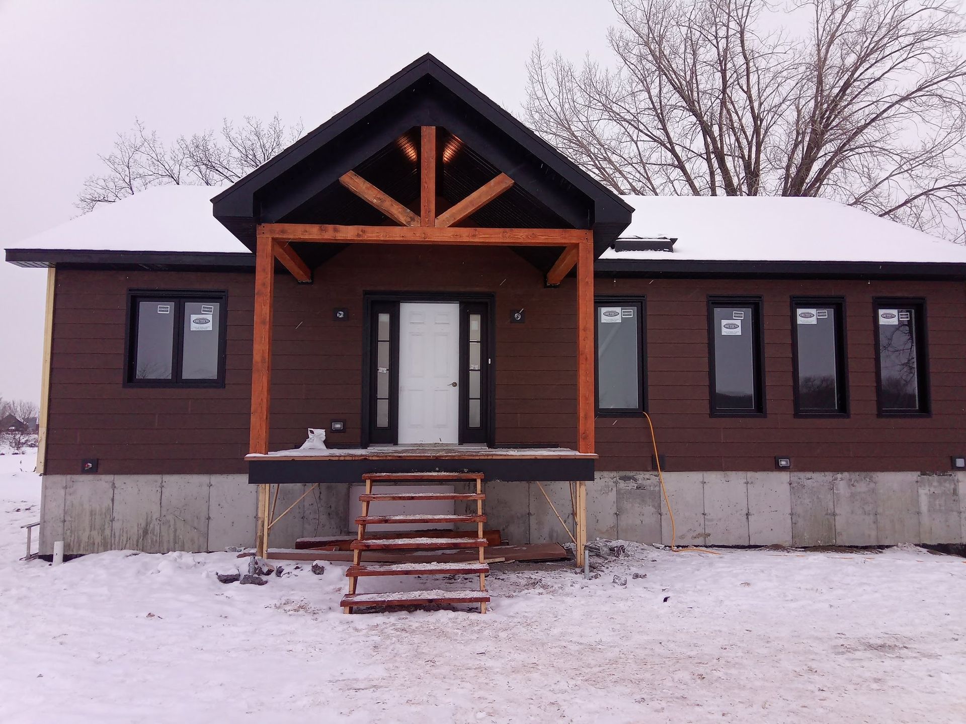 Une maison brune avec un porche et des escaliers dans la neige