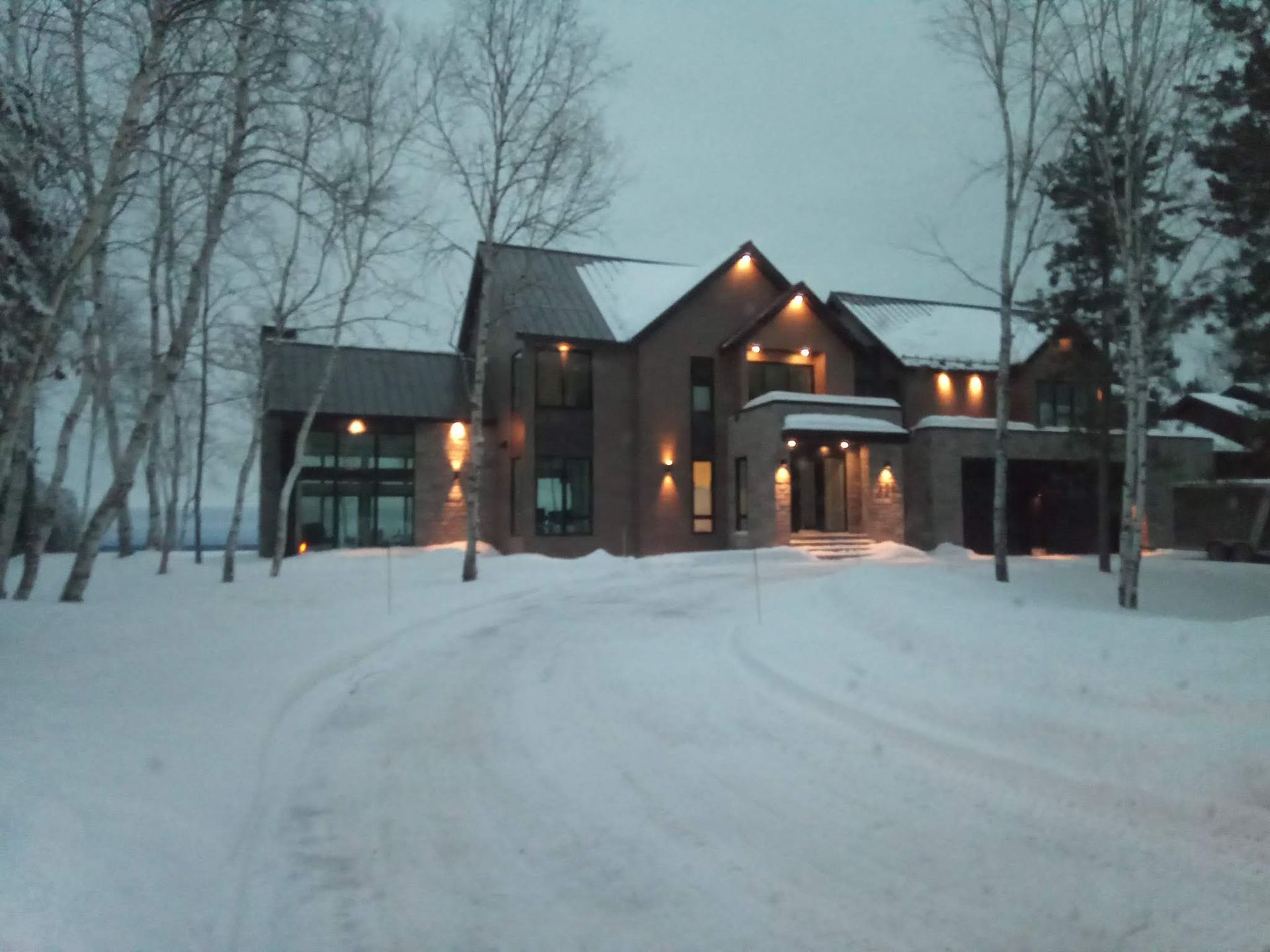 Une grande maison est entourée de neige et d'arbres