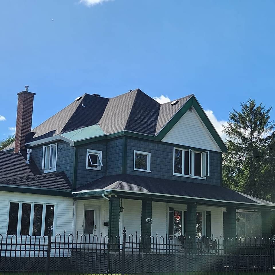Une maison avec une clôture autour et une cheminée sur le toit