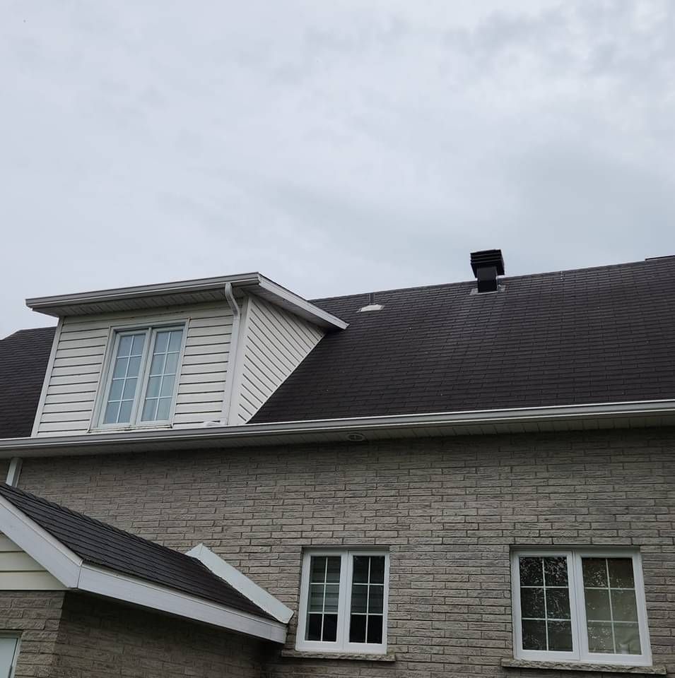 Une maison en brique avec un toit noir et des fenêtres blanches