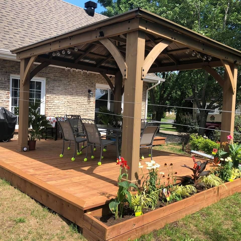 Une terrasse en bois avec pergola et chaises devant une maison en brique.