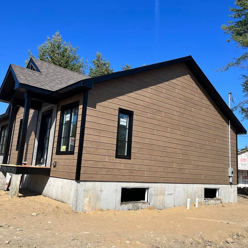 Une maison marron avec un toit noir et beaucoup de fenêtres