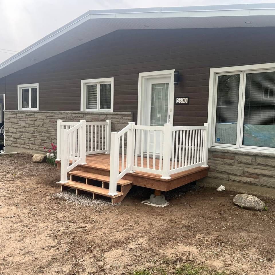 Une maison marron avec un porche et des escaliers blancs