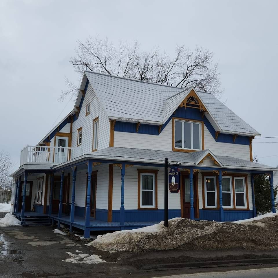 Une grande maison blanche et bleue avec un porche