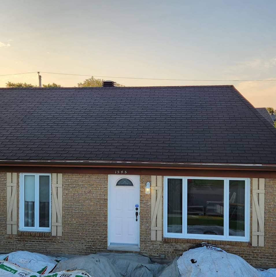 Une maison en brique avec un toit marron et des fenêtres blanches