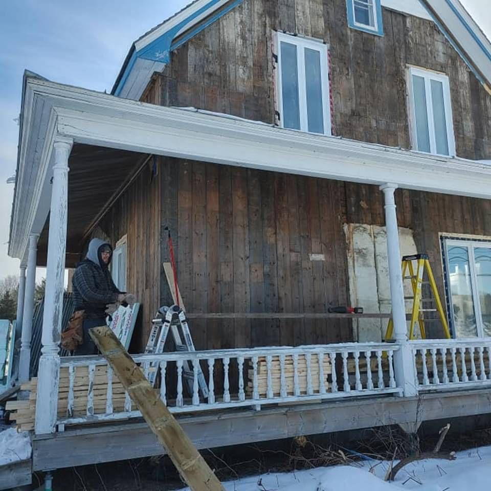 Un homme debout sur un porche avec une échelle devant une maison