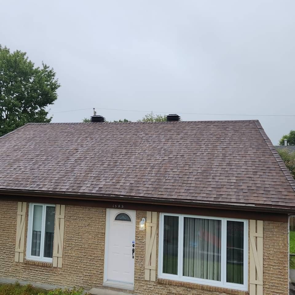 Une maison en brique avec un toit marron et des fenêtres blanches
