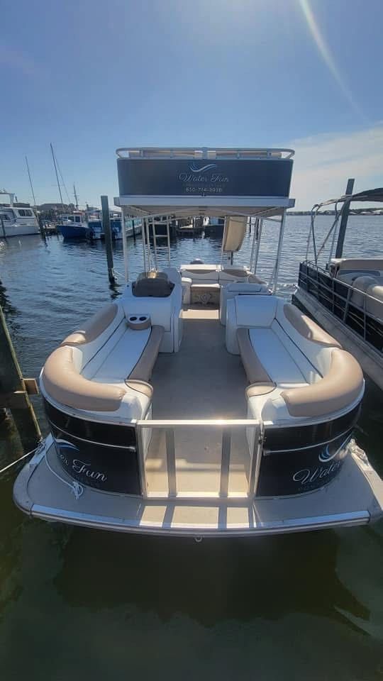 A pontoon boat is docked at a marina on a sunny day.