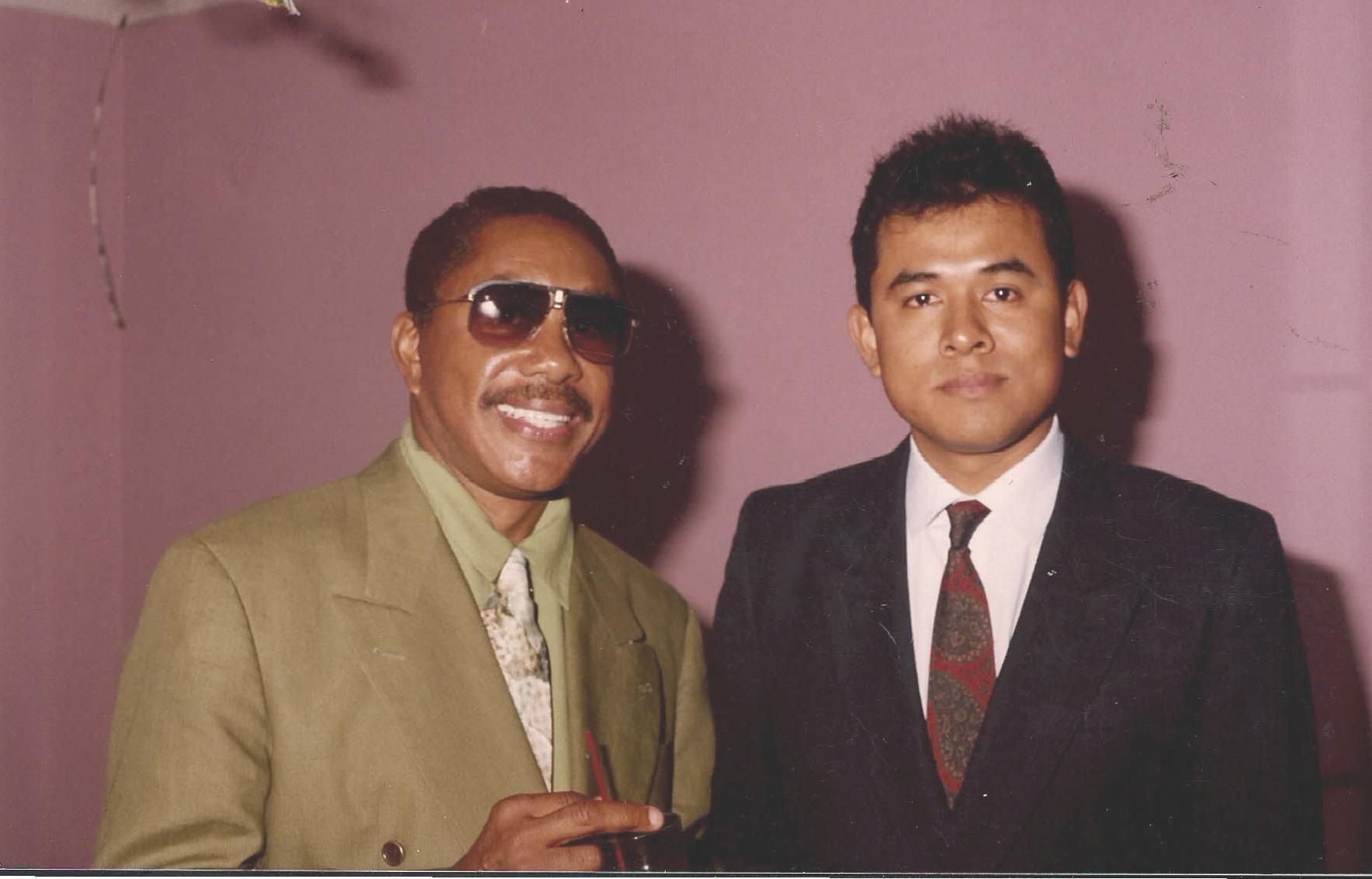 Two men are posing for a picture and one is wearing sunglasses