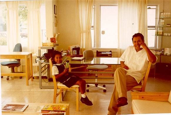 A man and a girl are sitting at a desk in a living room