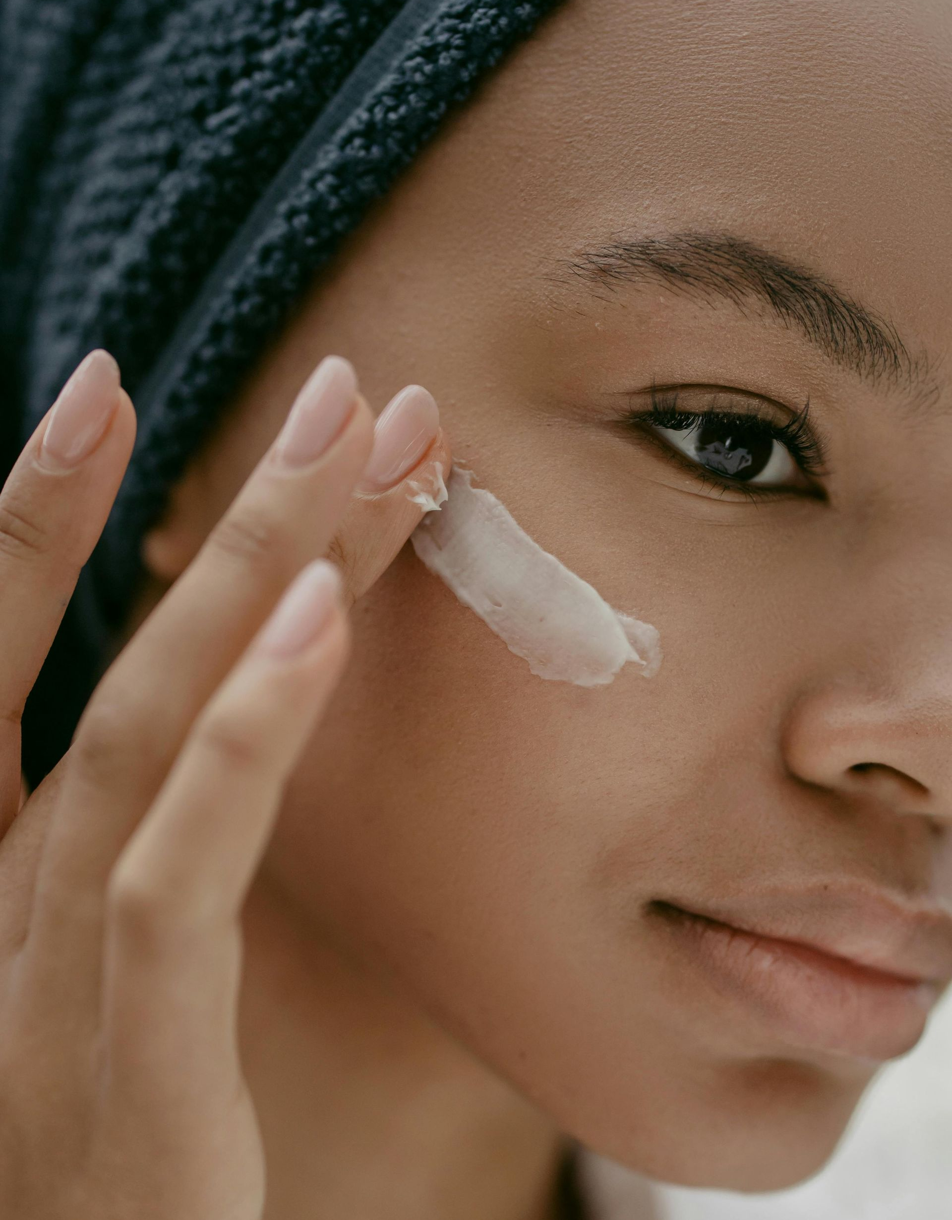 Woman applying cream to her face with fingers; close-up shot.