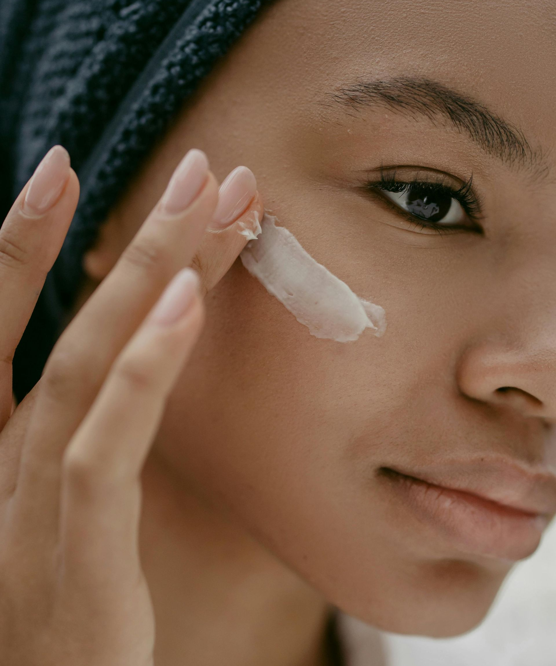 Woman applying cream to her face with fingers; close-up shot.