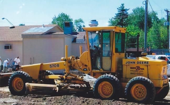 A truck is driving down a dirt road in front of a building