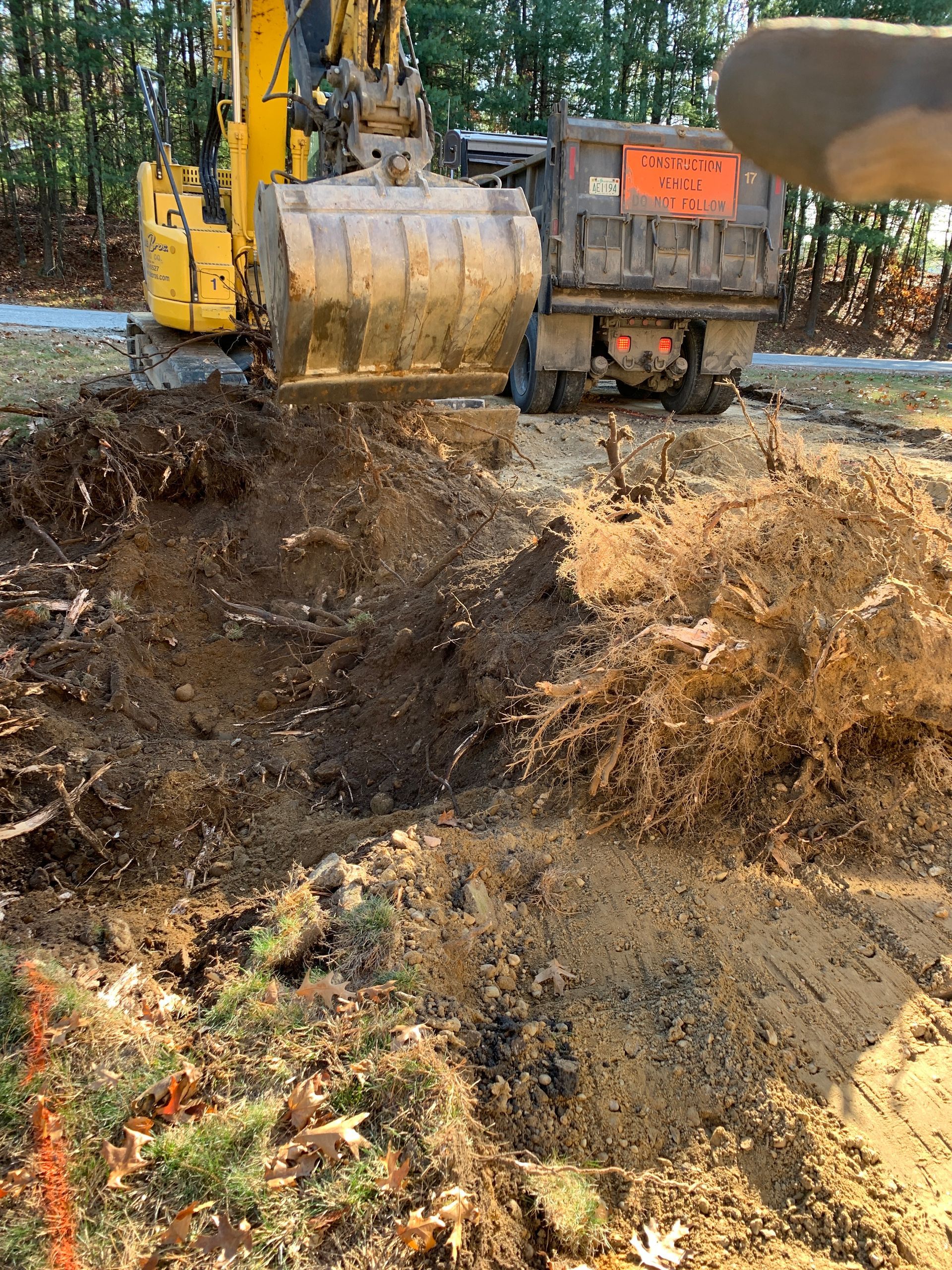 A yellow excavator is digging a hole in the ground