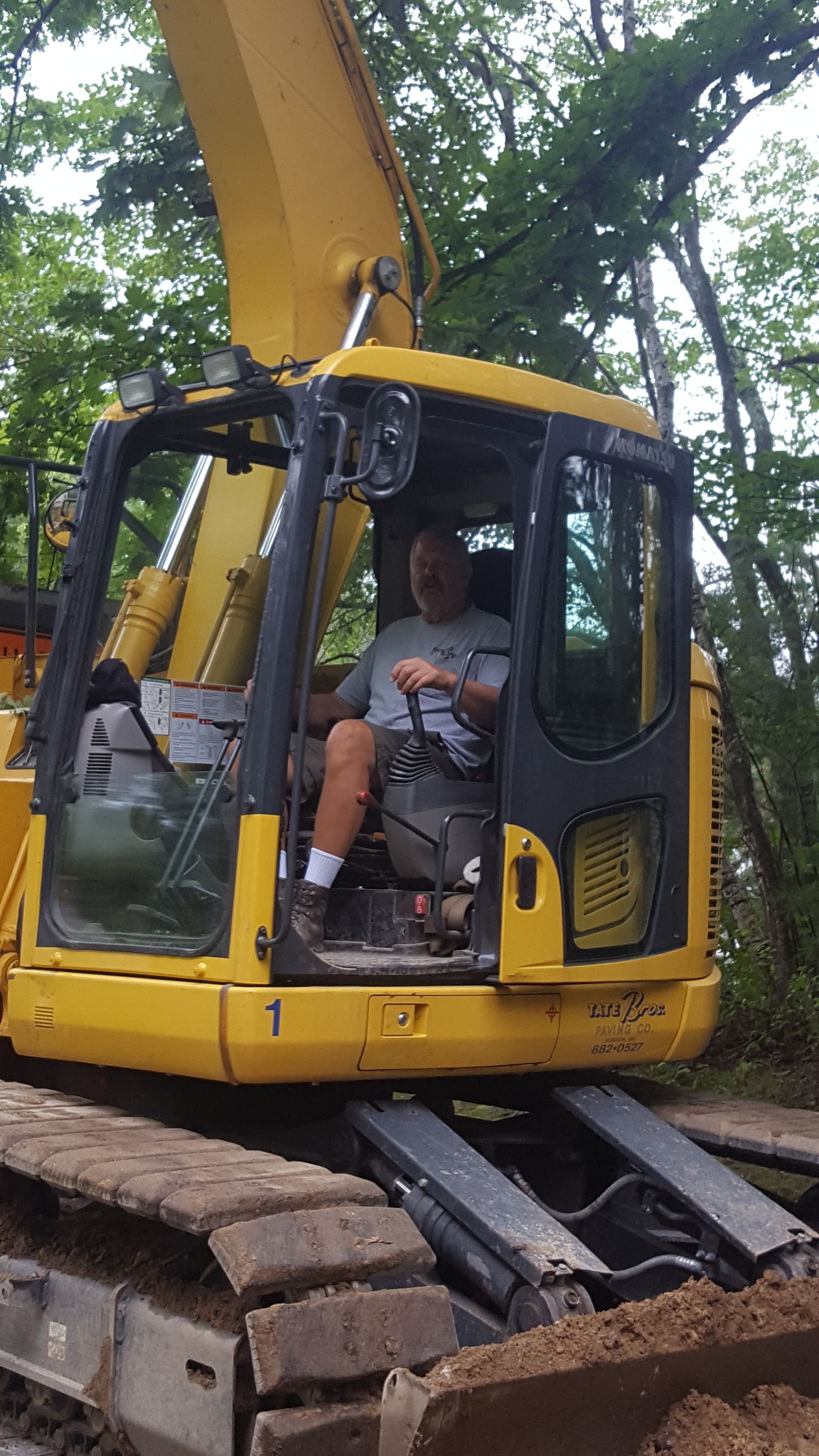 A man is sitting in the cab of a yellow excavator