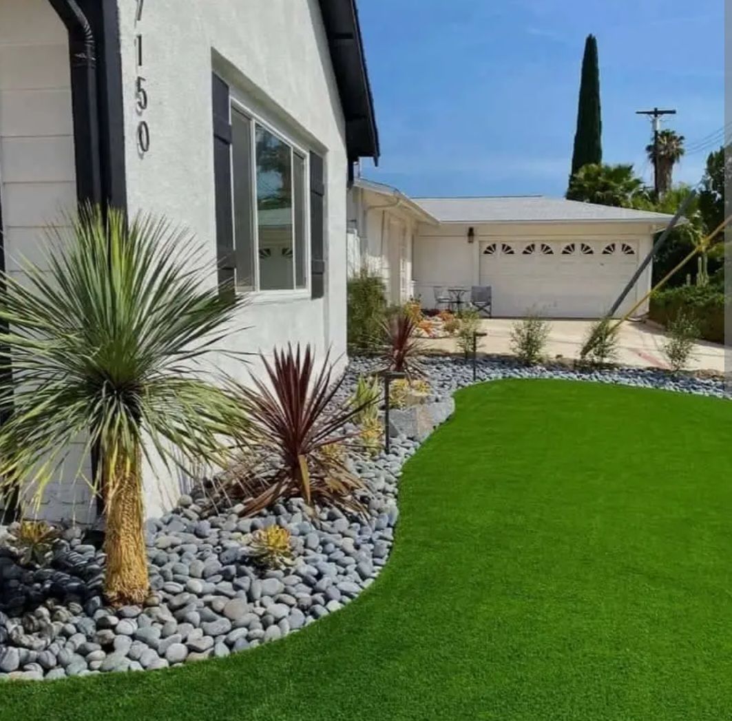 Modern house with desert landscaping, green artificial lawn, and a white garage under a clear blue sky