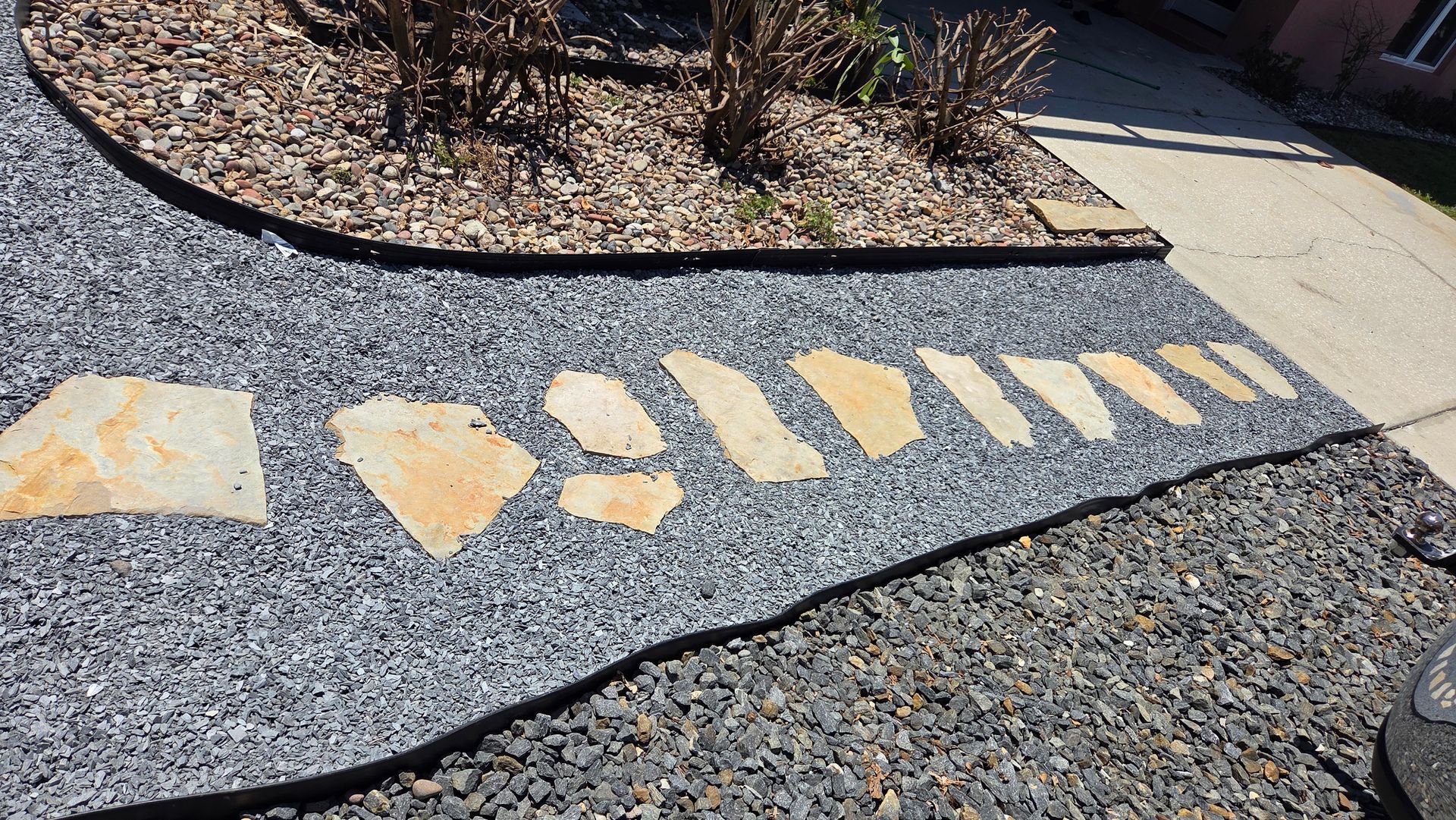Yellow painted markings on gravel beside a curving sidewalk in a landscaped outdoor area
