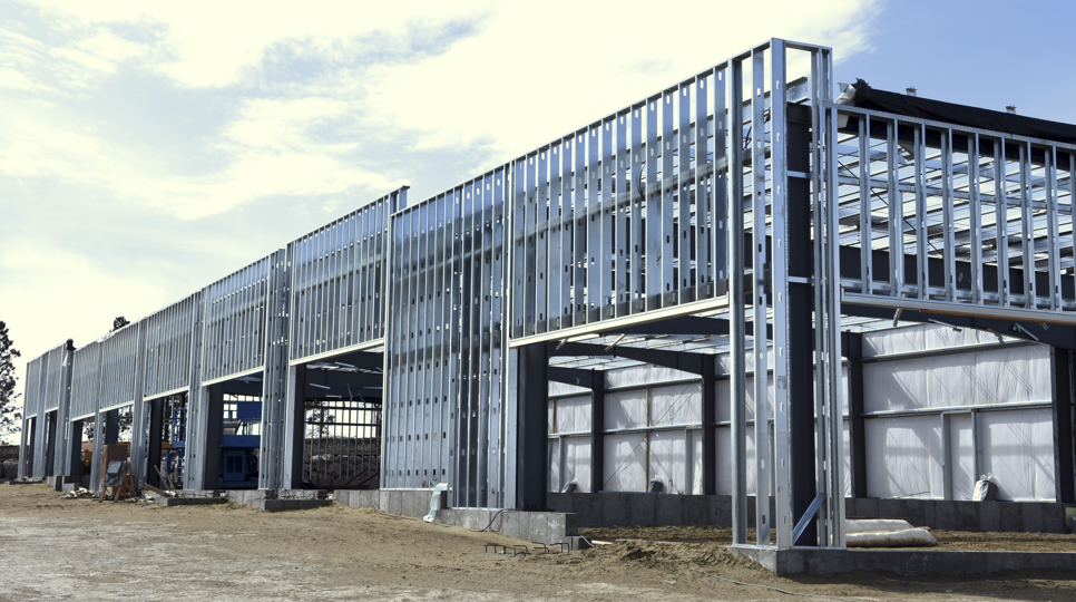 Steel frame of a building under construction against a blue sky.