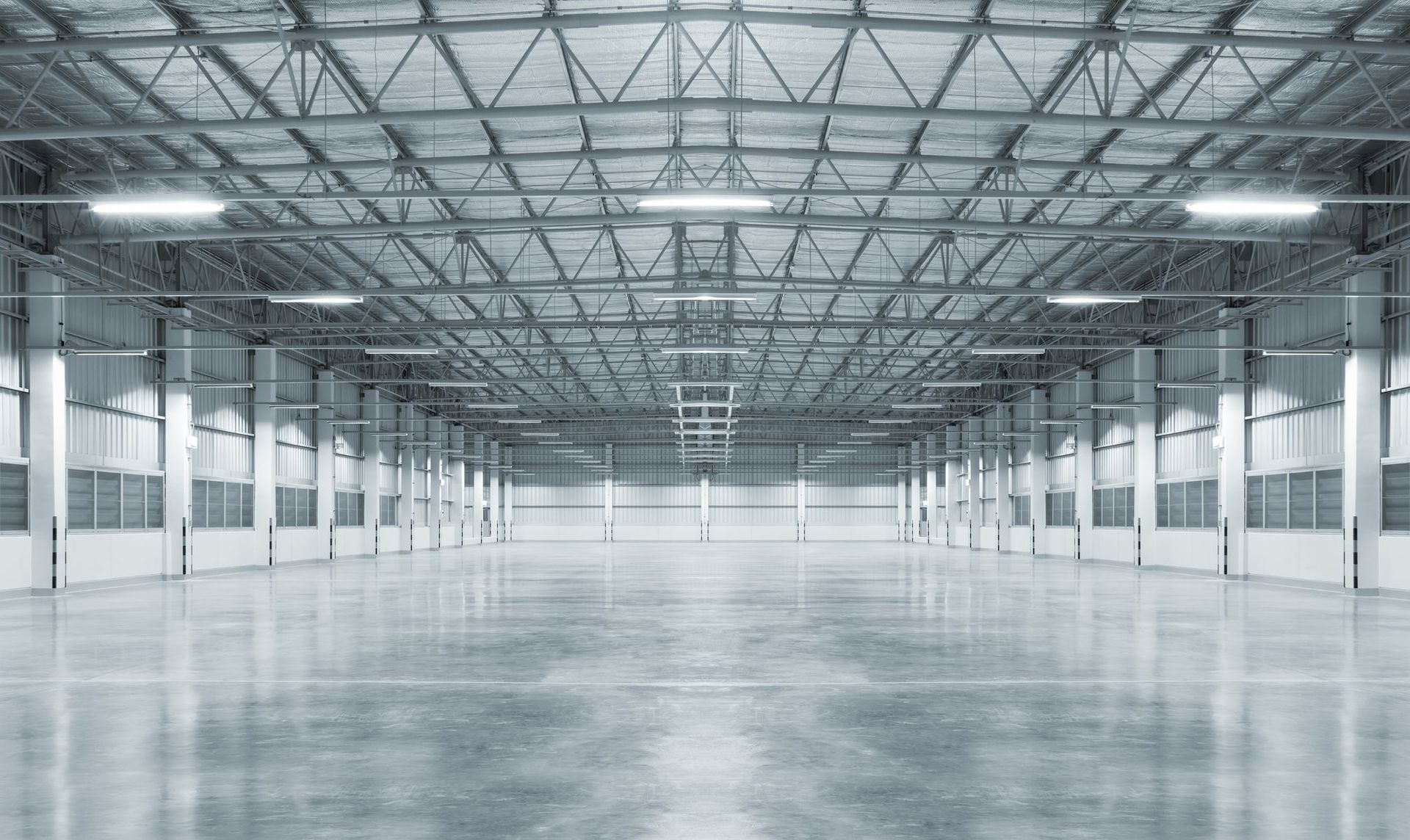 Empty, expansive warehouse interior with bright overhead lights and polished concrete floor.