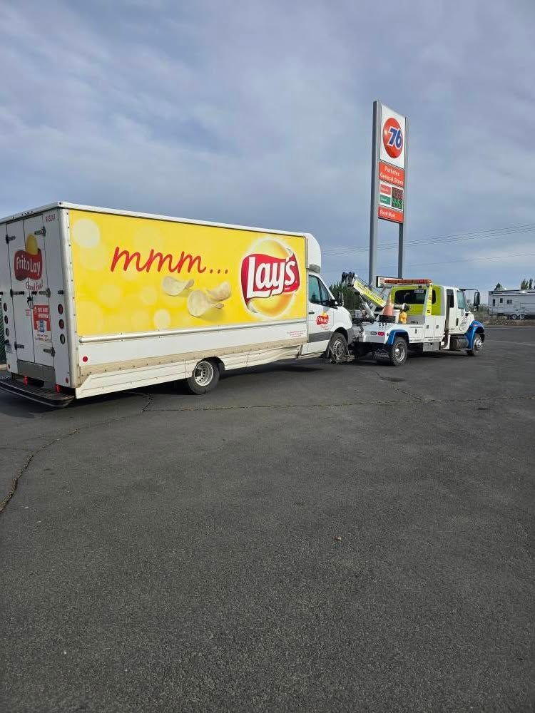 Lays delivery truck being towed at a gas station. The truck has the Lays logo.