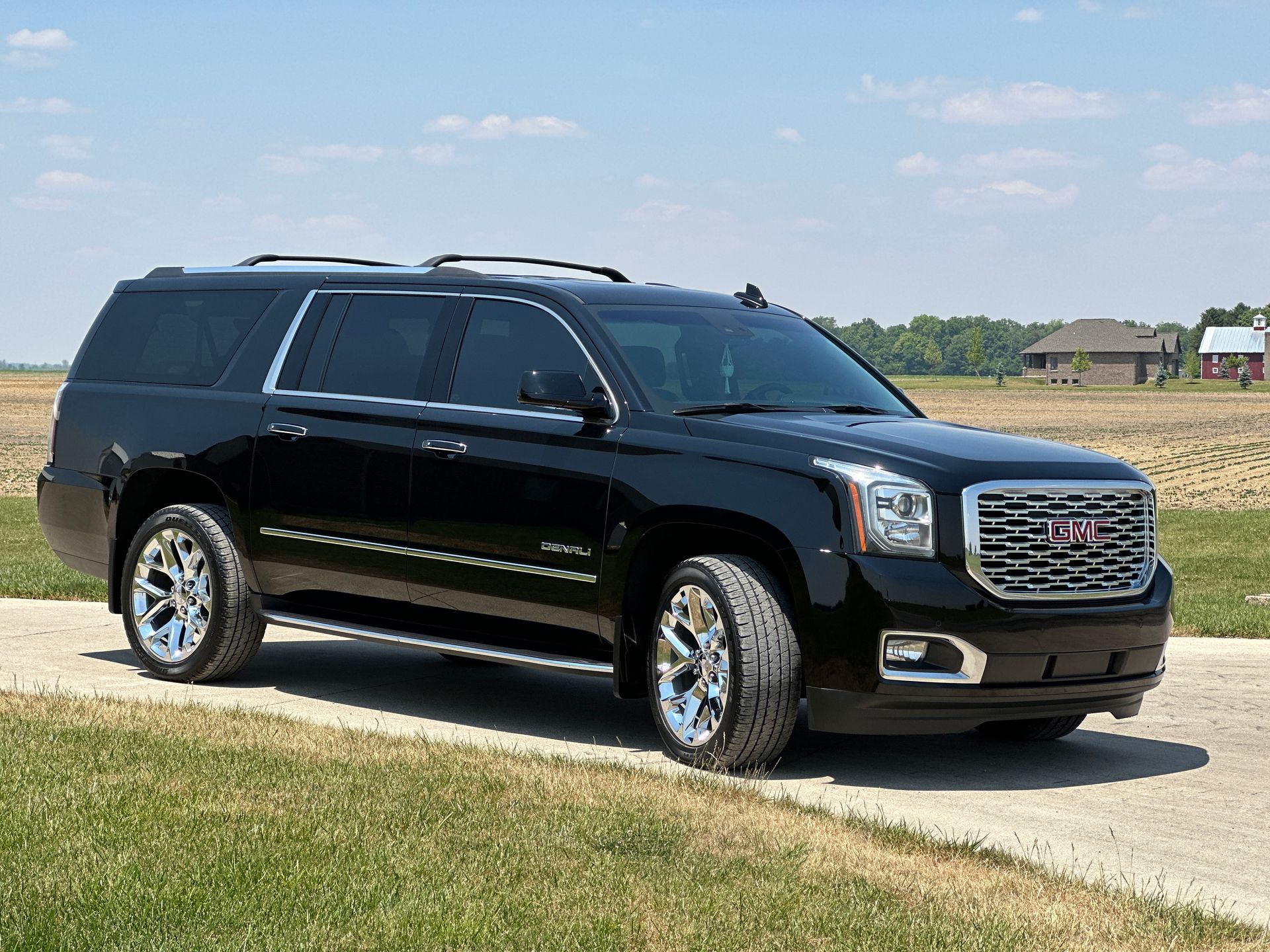 A black suv is parked on the side of a road next to a field.